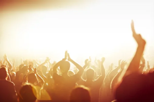A crowd with hands raised in worship, lit by golden light